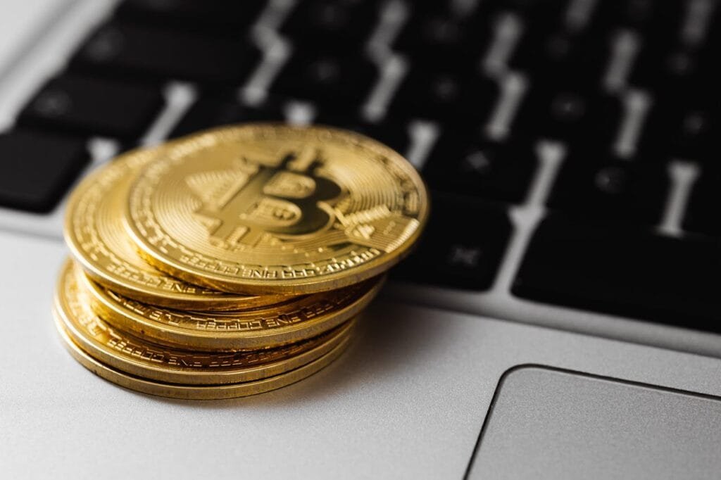 Stack of golden bitcoins on a laptop keyboard, symbolizing digital currency and wealth.